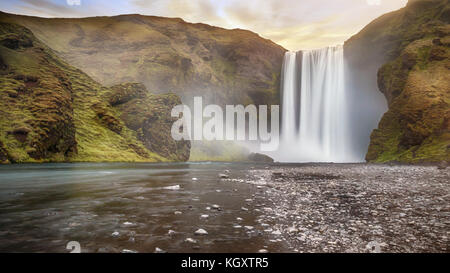 Long exposure of beautiful Skogafoss waterfall with spray over dramatic land. Pastel sky gives soft light. South Iceland. Stock Photo