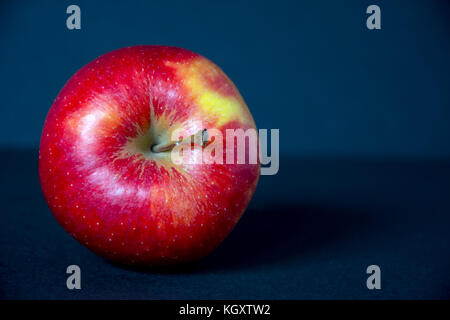 Whole, red, ripe, tasty apple with its stem pointing right on black background Stock Photo