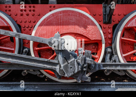 Red frame and wheels of a steam locomotive with cranks, rods and axles. Stock Photo