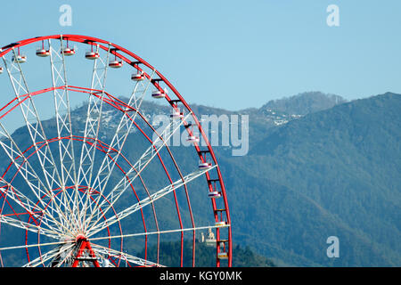 Part of the Ferris wheel against the backdrop of the mountains covered with forests. Stock Photo