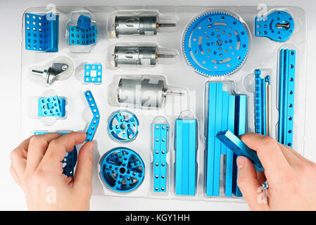 Unpacking DIY kit above view. Hands take metal part of rc model Stock Photo