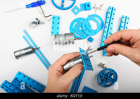 Modeling hobby concept. Hands putting screw in metal rc car parts Stock Photo