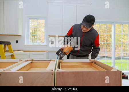 Young female carpenter using a nail gun while working in a workshop Carpenter using nail gun kitchen cabinets Stock Photo