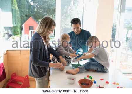 Young family feeding goldfish in bowl on kitchen counter