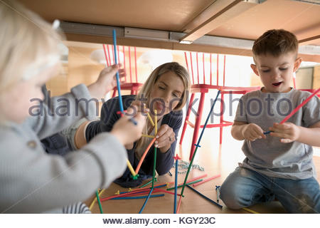 Mother and toddler children playing with connector sticks underneath table