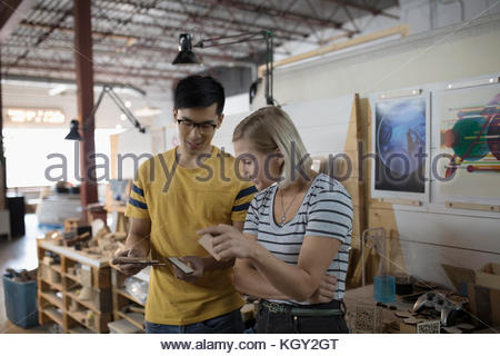 Small business owner craftspeople examining pieces in workshop