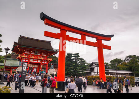 Lots of tourists visting the main entrance of Fushimi inari, with the principal shrine and the main red gate in Kyoto Stock Photo