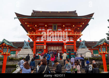 Lots of tourists visting the main entrance of Fushimi inari, with the principal shrine and the main red gate in Kyoto Stock Photo