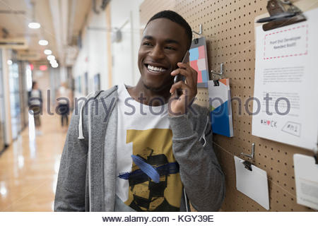 Smiling male freelancer talking on smart phone at message board in office