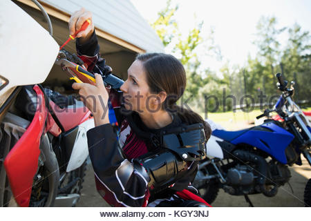 Woman fixing motorbike in driveway