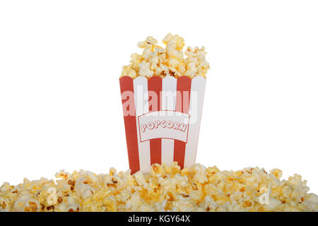One red and white stripped bag labeled POPCORN filled with fresh butter popcorn with the same spilling over pilled in front of the bag isolated on a w Stock Photo