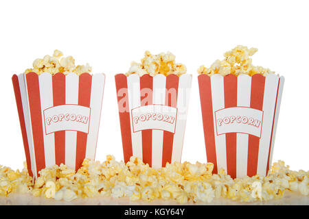 Three red and white stripped bags labeled POPCORN filled with fresh butter popcorn with the same spilling over onto a reflective surface isolated on a Stock Photo