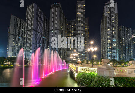 A state of the art fountain at night with colorful lights shimmering, behind the skyscrapers Stock Photo