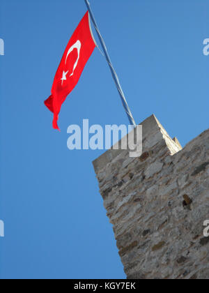 The Turkish national flag flying above the stone ramparts of Marmaris Castle, Turkey Stock Photo