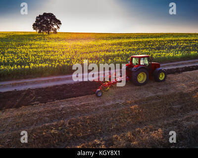 Farmer in tractor preparing land with seedbed cultivator, aerial view Stock Photo