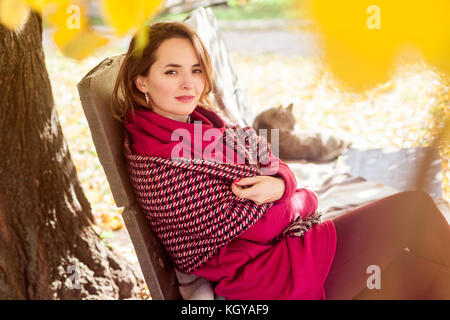 Autumn weather. Leisure woman sit near cat in park. Outdoor shot in park Stock Photo