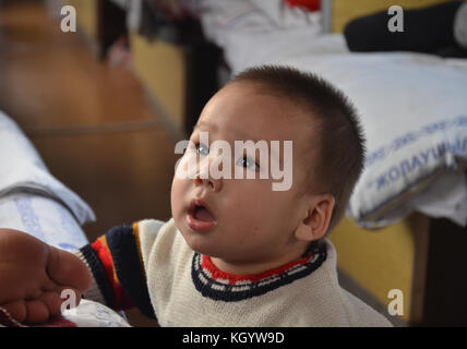 little cute Kazakh baby boy with Asian with cockeyed eyes staring to ...