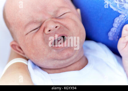 Infant baby boy in mother's arms starting to cry Stock Photo