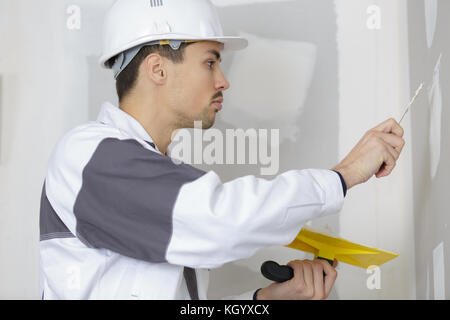 builder in hardhats with plastering tools indoors Stock Photo