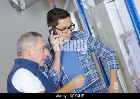 two workers talking and holding tablet pc and mobile phone Stock Photo