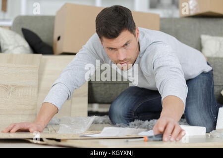 man at home assembling flat pack furniture Stock Photo