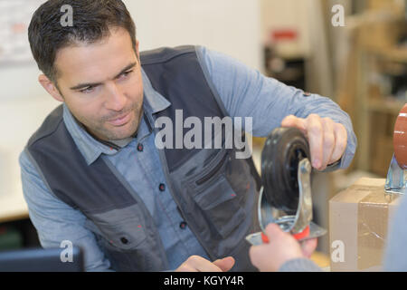 man repairing trolley wheel in workshop Stock Photo