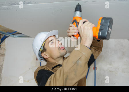 young worker drilling ceiling Stock Photo