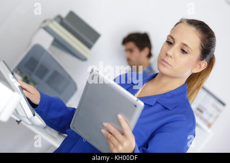 technician holding digital tablet while examining photocopier Stock Photo