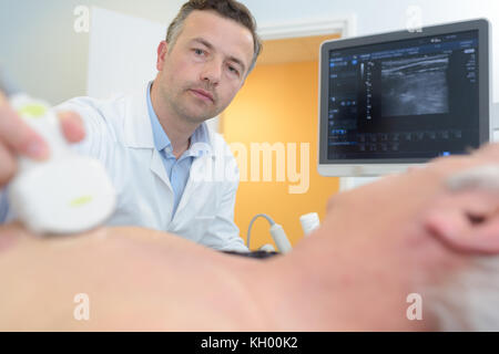 doctor placing ultrasound probe on male patients chest Stock Photo