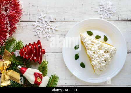 A large piece of delicate sponge cake decorating air cream. Festive dessert on a white background. To celebrate Christmas, New Year's Eve. The top vie Stock Photo