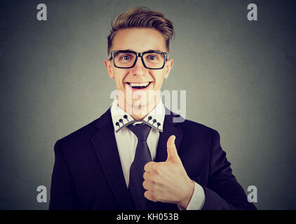 Closeup of a happy man giving thumbs up gesture isolated on gray background Stock Photo