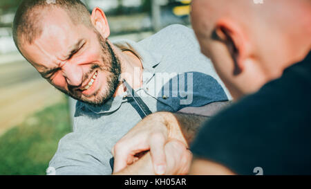 Kapap instructor demonstrates martial arts self defense knife attack disarming technique against threat and knife attack. Weapon retention and disarm  Stock Photo