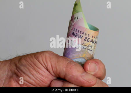New Zealand dollars clutched in a hand. Stock Photo