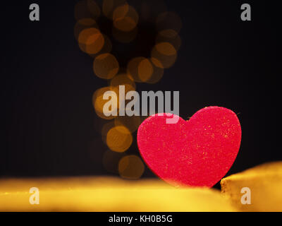 Close up of a red wooden heart shape with blurred heart shaped lights in the background Stock Photo