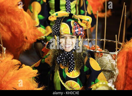 A smiling samba dancer from samba school Grande Rio is dressed in a carnival costume and dances down the Parading Avenue at the Sambodromo. Brazil 03.03.2014. Stock Photo