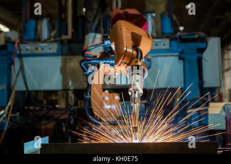 Orange robot is welding in car factory Stock Photo