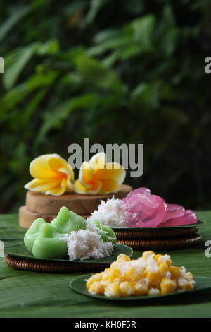 Three kinds of Jaja Bali, or Balinese cake, served individually on banana leaf rounds; then arranged on a table lined with large banana leaf. Stock Photo