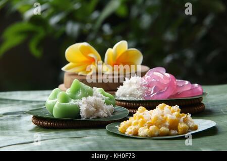 Three kinds of Jaja Bali, or Balinese cake, served individually on banana leaf rounds; then arranged on a table lined with large banana leaf. Stock Photo
