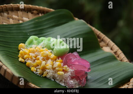 Three kinds of Jaja Bali, or Balinese cake, served together on woven bamboo plate lined with banana leaf. Stock Photo