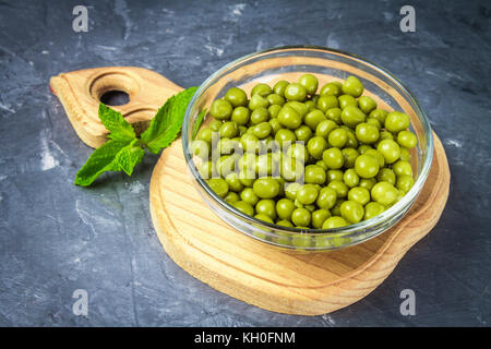 Canned peas in a wooden plate on a gray concrete background Stock Photo