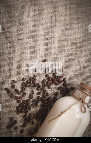 bottle of milk and loose coffee beans on background of linen Stock Photo