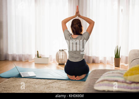 Full length shot of a woman doing yoga  at home Stock Photo