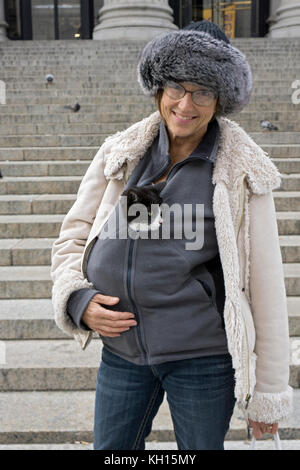 Portrait of a middle aged woman  who is keeping her cat warm on a chilly autumn day in Midtown Manhattan, New York City. Stock Photo