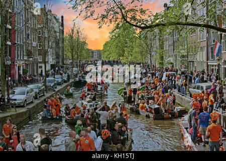 AMSTERDAM, NETHERLANDS - APRIL 27: People celebrating Kings day on the canals on April 27, 2017 in Amsterdam, The Netherlands at sunset Stock Photo