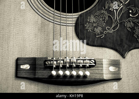 Sepia-toned close-up image of the bridge and sound hole of a 1970s Yamaha FG-300 acoustic steel-strung guitar Stock Photo