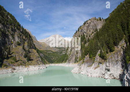 GIBIDUM DAM, NATERS, SWITZERLAND - September 22, 2017: View over the grey and blue lake of the hydroelectric power dam towards an alpine landscape. Stock Photo