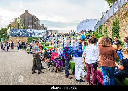 People socialising on the artificial-grassed steps at Granary Square, King's Cross, London, UK, by the Regent's Canal, 2017 Stock Photo