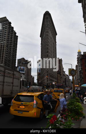 Man exiting yellow cab, and cast iron clock in front of the Flatiron Building, New York City. Stock Photo