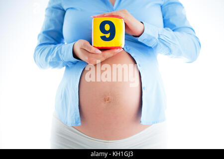 9 months pregnant. Close up of a cute pregnant belly, studio shot. Stock Photo