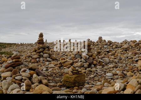 Man made stacks of stone / cairns - lining the east beach of Holy Island Stock Photo